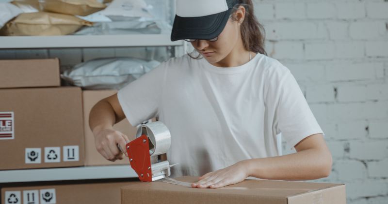 Person securing freight for shipping with tape and label