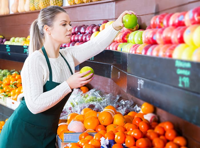 female produce manager stocking fruit on shelf