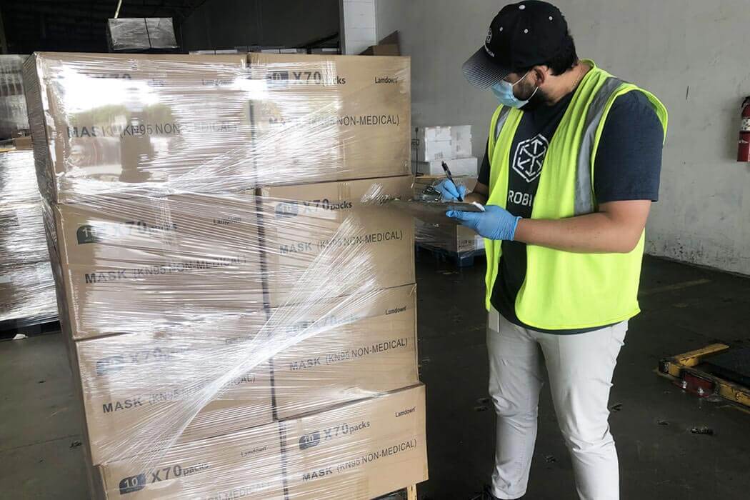Worker with PPE next to wrapped pallet