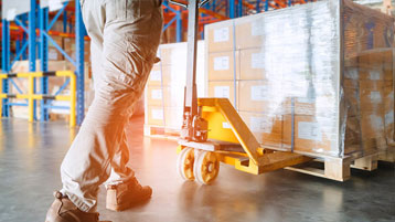 dock worker moving a pallet of parcels for less than truckload order