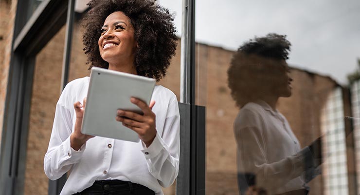 Person of color smiling with a tablet