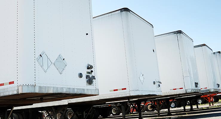 Close up crop of 4 drop trailer freight shipping trucks