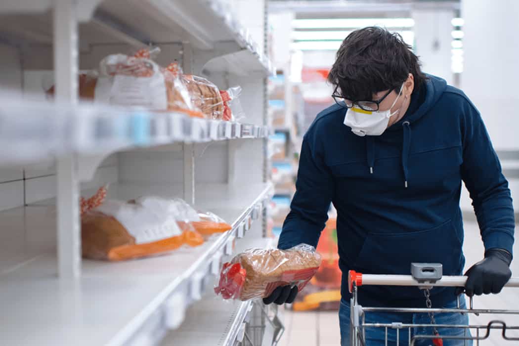 Man shopping near empty shelves in PPE