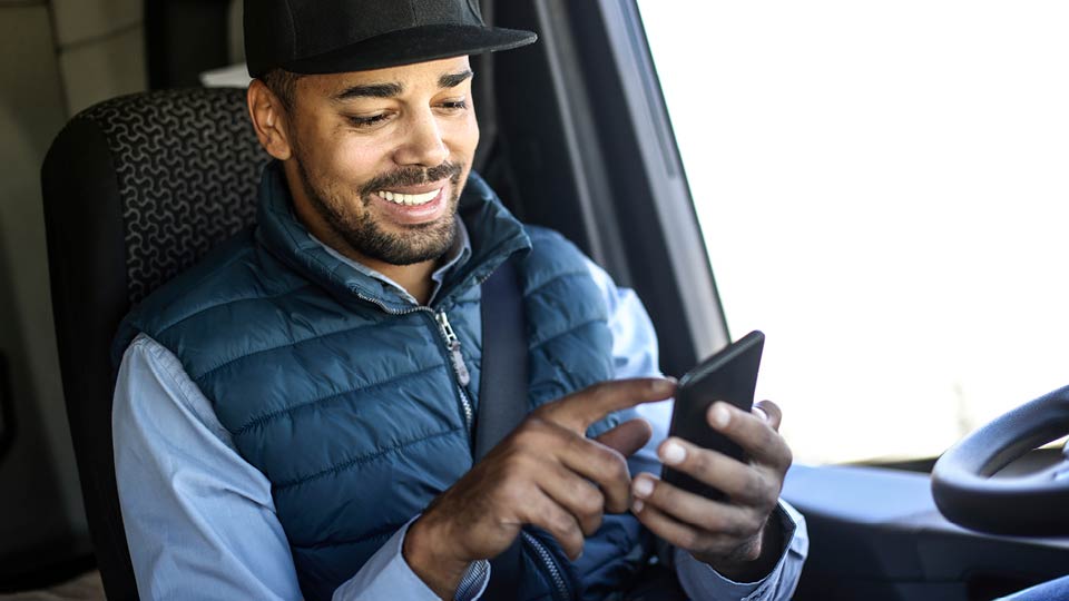 Male driver smiling at mobile device in his hands