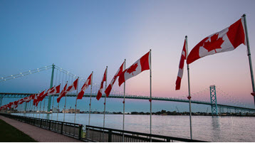 Row of Canadian flags along the waterfront at dawn